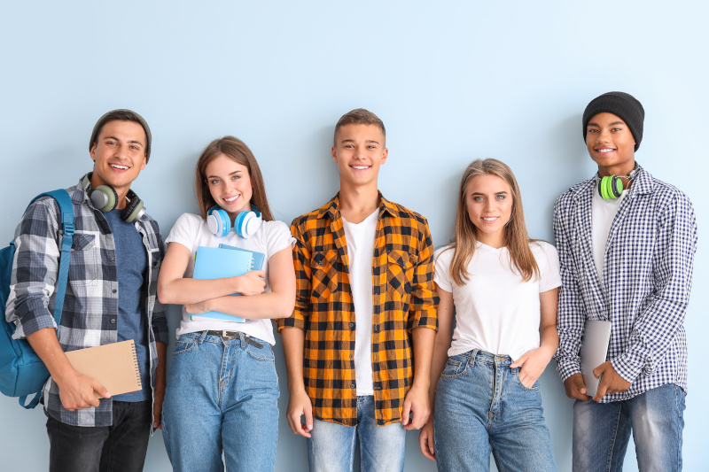 5 fröhliche junge Personen vor einer blauen Wand