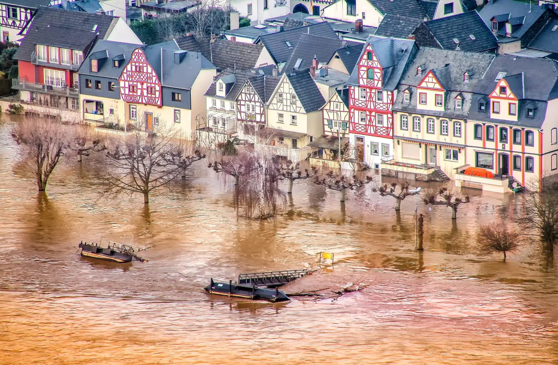 Foto einer Überschwemmung. Häuser und Bäume stehen teilweise im Wasser.